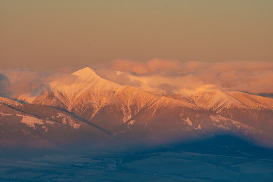 Aerial view of Baranec peak in the Western Tatras covered in snow during golden hour with soft clouds Jamnik, Zilina Region, Slovakia.