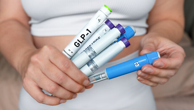 Woman holding multiple GLP-1 injection pens, weight loss and diabetes treatment concept