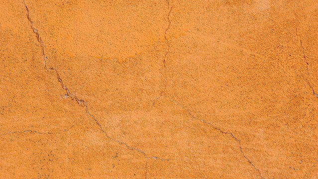 Orange plaster wall texture with cracks, rough stucco background