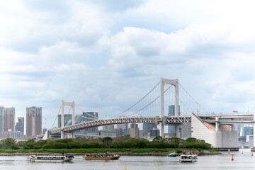 Fototapeta premium Rainbow Bridge with boats on Tokyo Bay, cityscape of Tokyo Japan, urban waterfront and transportation scene 東京湾に架かるレインボーブリッジと船の風景 都市のウォーターフロント景観