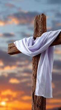 Rustic wooden cross draped with white cloth against a colorful sunset sky for easter background and banner design