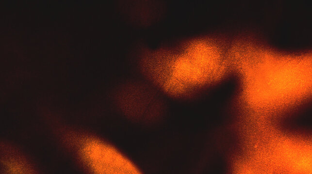 Close up of burning orange and red fire flames glowing with hot heat and energy against a dark black background in a seamless motion loop