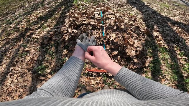 Gardener rakes dry oak leaves with a rake in the garden. First person view (POV). Spring or autumn cleaning of the garden. The process of raking fallen leaves in the garden with an orange rake. Work