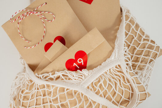 top view on string bag full of advent calendar recycled craft bags white background. eco-friendly christmas concept