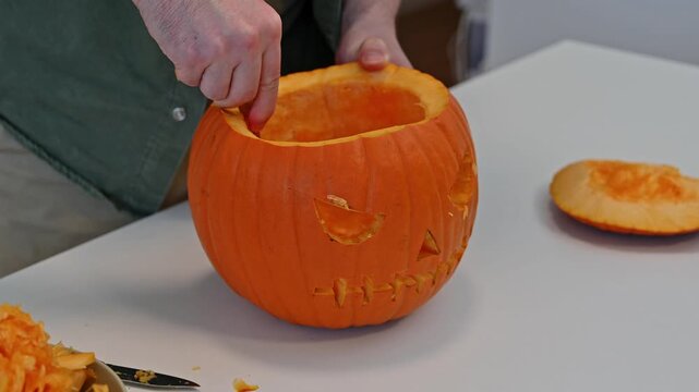 Closeup man's hands carving jack o lantern for halloween celebration