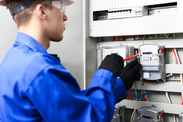 Electrician with screwdriver checking electrical meter indoors, closeup