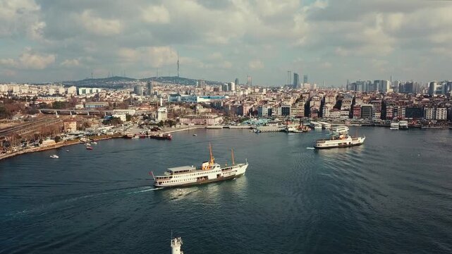 Classic Istanbul passenger ferries approaching Kadikoy ferry pier with lighthouse, Camlica Tower and Asian side cityscape in background, aerial view, Istanbul, Turkey 