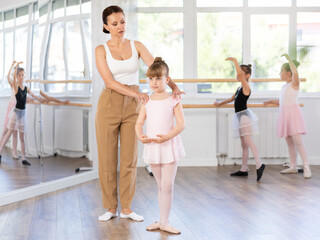 Ballet lesson for little girls - choreography teacher shows little ballerinas how to get into different poses correctly © JackF