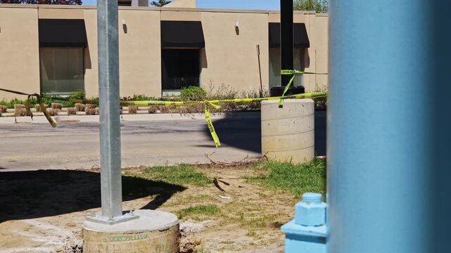 Workers set up safety measures around construction areas near buildings. Yellow tape marks off restricted zones as work continues to improve the location during the day.