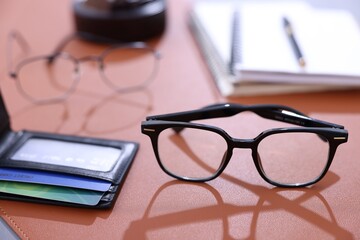 Stylish glasses and personal belongings on brown table, closeup