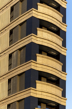 View of modern residential building facade with curved balconies and stone textures under a clear blue sky Taipei City, Taiwan.