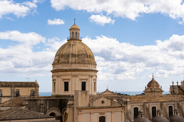 Fototapeta premium Architectural view of a historic dome structure in Noto, Italy, showcasing intricate details against a backdrop of blue sky and scattered clouds