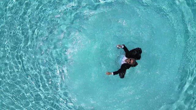 Summer funny freelancer lifestyle. Creative summer business scene. Wet business man in suit with laptop swimming in pool. Summer remote work in swimming pool. Unusual workplace idea.