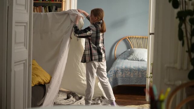 White girl exploring blanket fort interior, child crawling into cozy tent, inspecting cushions, peeking under drape, playful discovery, room light, bedroom .