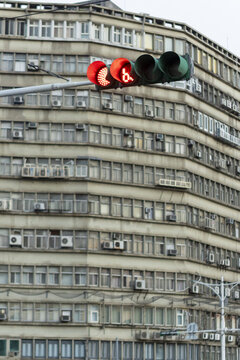 View of a red traffic light with a digital countdown timer in front of a large grey apartment building with many windows and air conditioning units Taipei City, Taiwan.
