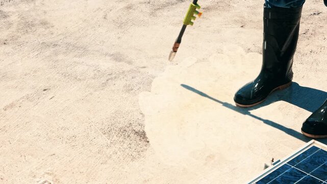 Worker using a high pressure water cleaner on a dirty roof