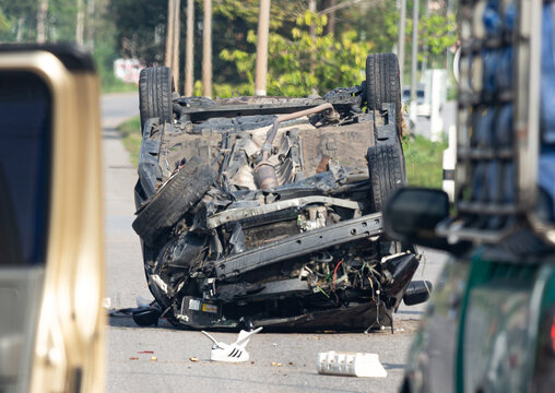 Scene of a severe traffic accident with an overturned car on a public road showing heavy damage
