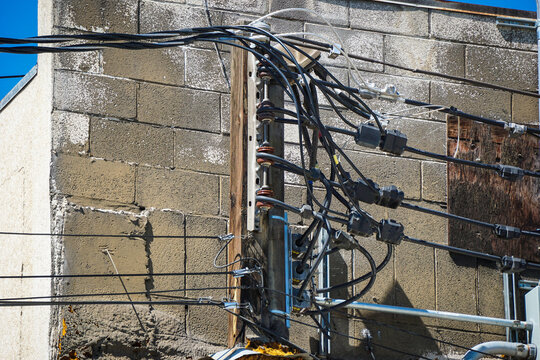 Old worn electrical power wires on urban building