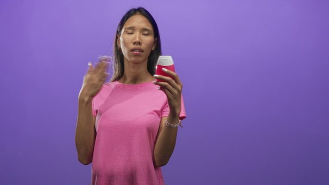 Young woman holding toothpaste bottle and touching neck while applying product in studio; self care concern.