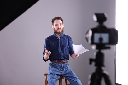 Actor with script rehearsing on light grey background