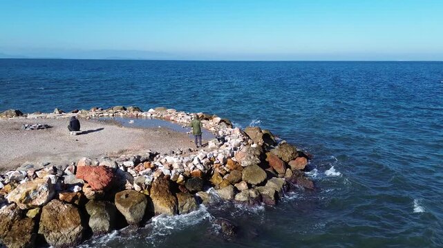 Aerial View of Man Fishing by the Sea in Izmir Turkiye Drone Shot