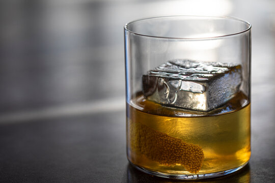 Glass of alcohol with large square ice cube
