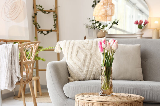 Vase with tulips on basket near sofa in living room