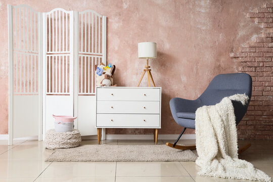 Interior of room with baby bag on commode and rocking armchair