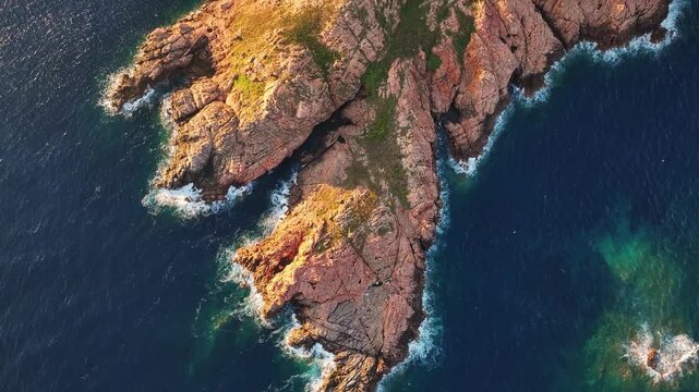 Aerial view of the dramatic red rock formations and turquoise Mediterranean waters at Costa Paradiso, Sardegna, Italy.