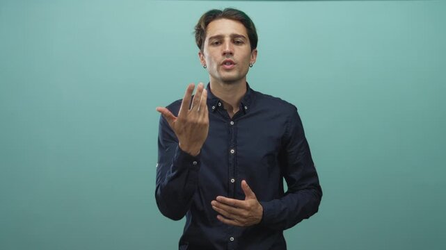 Man in navy shirt gesturing with open hands and visible palm, facing camera in studio; thoughtful persuasion.
