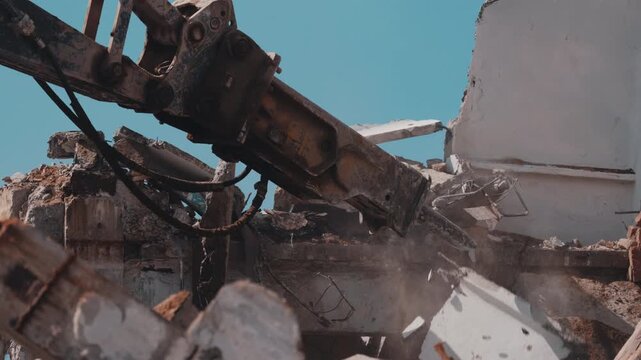 Excavator hydraulic hammer demolishing concrete slabs during building teardown close up