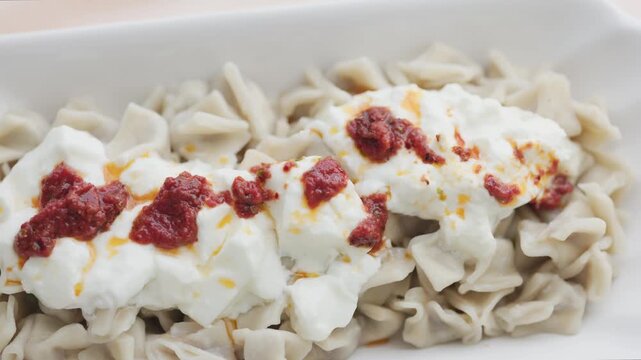 Close-up of traditional Turkish Manti with yogurt and red pepper sauce	