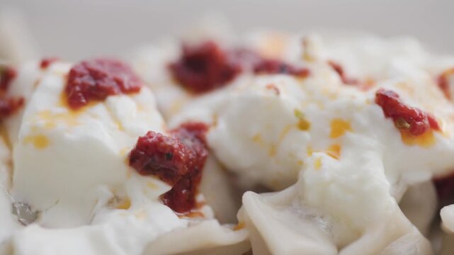 Close-up of traditional Turkish Manti with yogurt and red pepper sauce