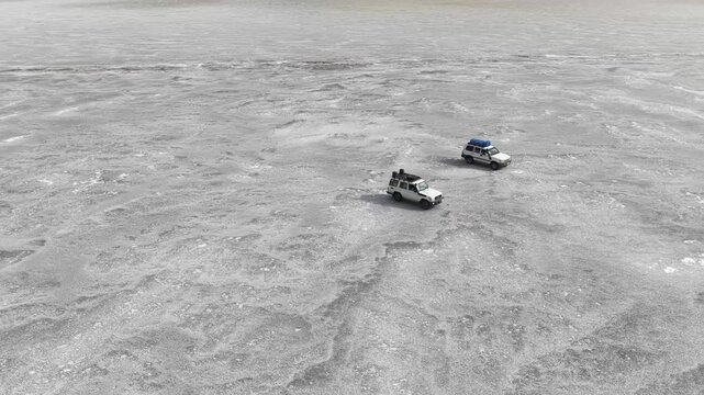 Aerial view of off-road vehicles parked on the vast white salt crust of the Danakil Desert under bright light in Dalol, Afar, Ethiopia.