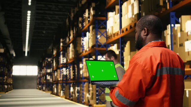 Mockup screen on laptop in industrial warehouse with black worker performing order fulfillment tasks. Workforce create professional logistics setting ready for e-commerce shipment.