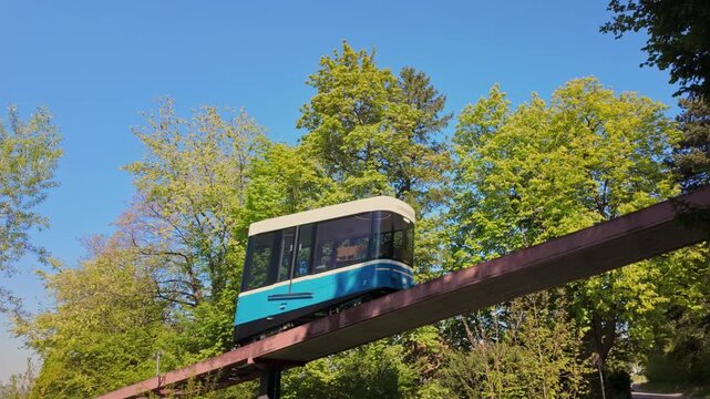Blue Rigiblick funicular cabin in Zurich on elevated track through green forest