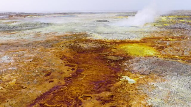Aerial view of the vibrant sulfur springs and mineral deposits in the Danakil Desert with steam rising from the ground in Dalol, Afar, Ethiopia.