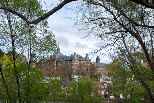 Historic Saint John's Seminary building from Gallagher Park framed by spring trees in Brighton neighborhood Boston, Massachusetts