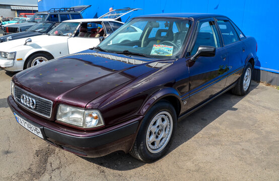 Dark burgundy Audi 80 (B4) sedan parked at an outdoor car show. The classic German car features signature alloy wheels and sits in a row of vintage vehicles