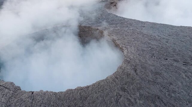 Aerial view of Erta Ale Volcano crater with thick white steam rising from the volcanic pit over the rugged lava field in Danakil Desert, Afar, Ethiopia.