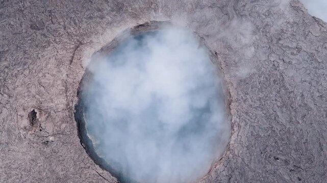 Aerial view of Erta Ale Volcano crater with thick white smoke rising from the vent over solidified lava fields in Danakil Desert, Afar, Ethiopia.