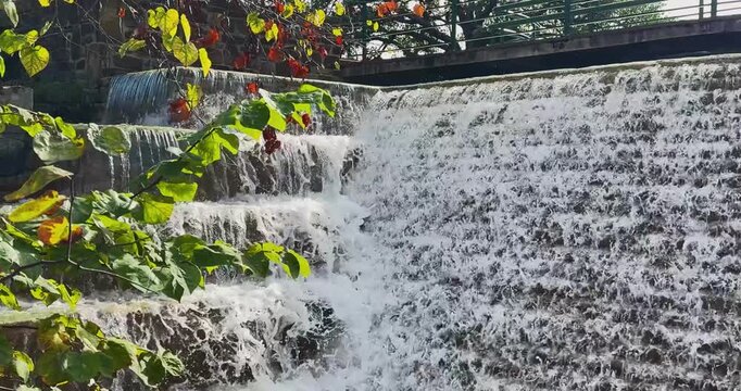 Closeup of a slow-motion cascading waterfall, concrete water feature in a commercial, intuitional garden.
