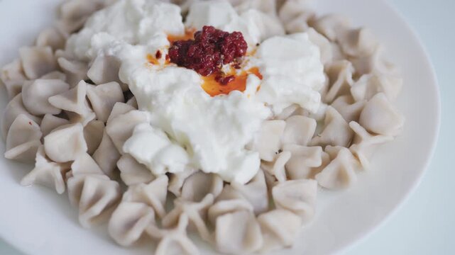 Close-up of traditional Turkish Manti with yogurt and red pepper sauce
