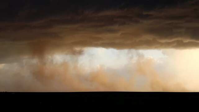 Dust blows in the wind and rises into the clouds as a wind storm tears across a flat landscape in this time lapse footage.