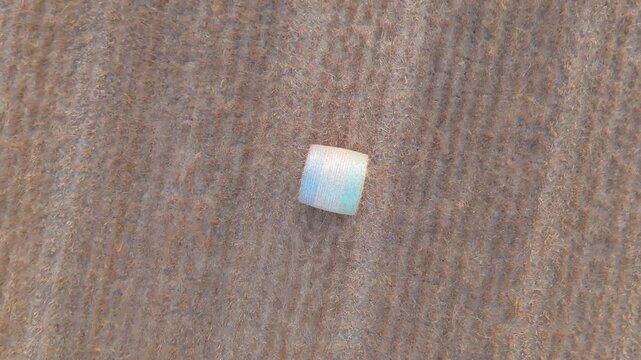 Aerial view of a single round hay bale wrapped in blue and green netting sitting in a dry harvested field in Geneva, Geneva, Switzerland.