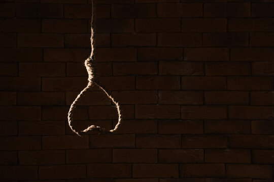 Hanging rope with loop on dark brick background. Suicide concept
