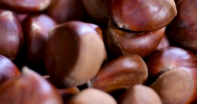 Light brown chestnuts in dishes, a full bowl of chestnut fruits stands on textured wood in the rustic kitchen interior.