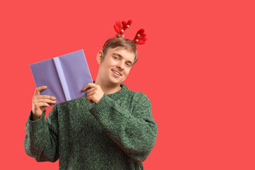 Naklejka premium Young man with book on red background. Christmas celebration