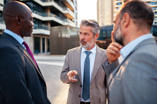 Senior executives discussing strategy outdoors in modern business district
