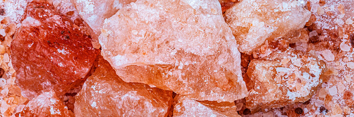 Fototapeta premium Large pieces of pink salt sit on a surface in a close-up view during daylight